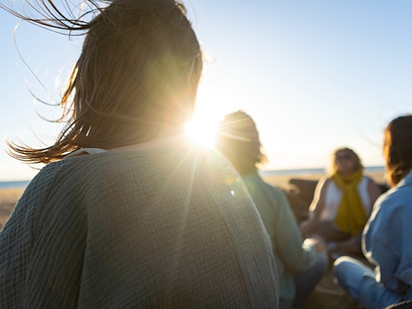 group of women sitting talking on beach on sunny windy day